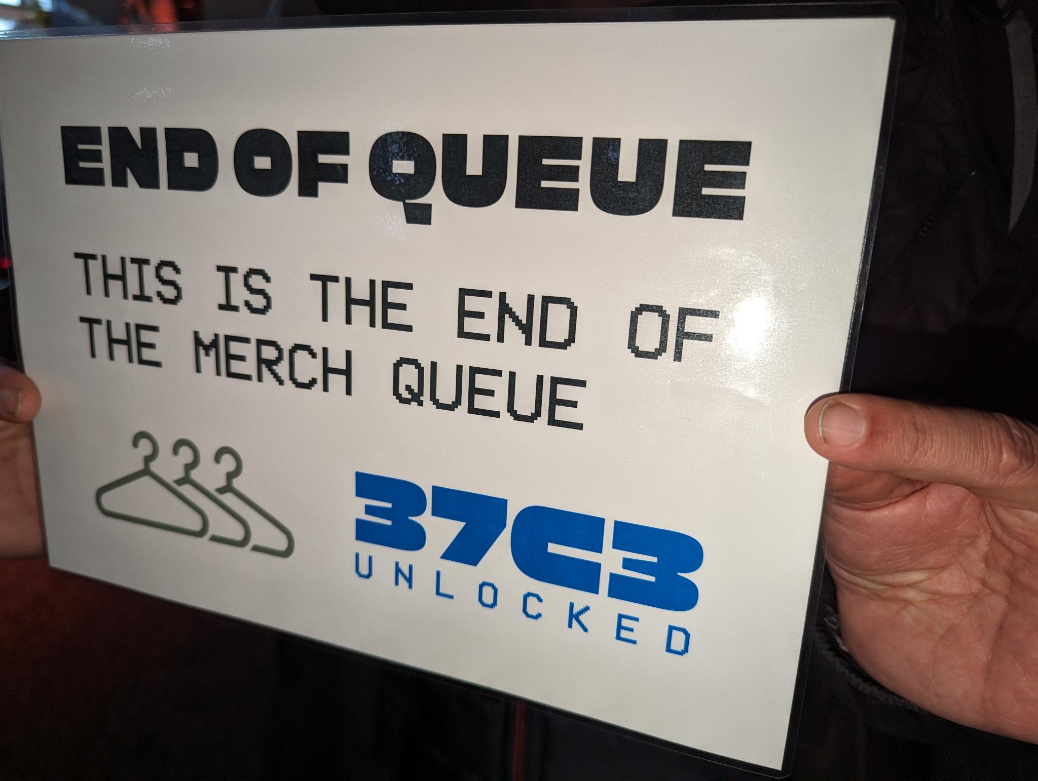 A sign titled "END OF QUEUE", with the description "THIS IS THE END OF THE MERCH QUEUE"