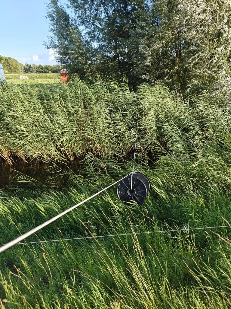 a picture of a cable roll being pulled over a canal by means of rope