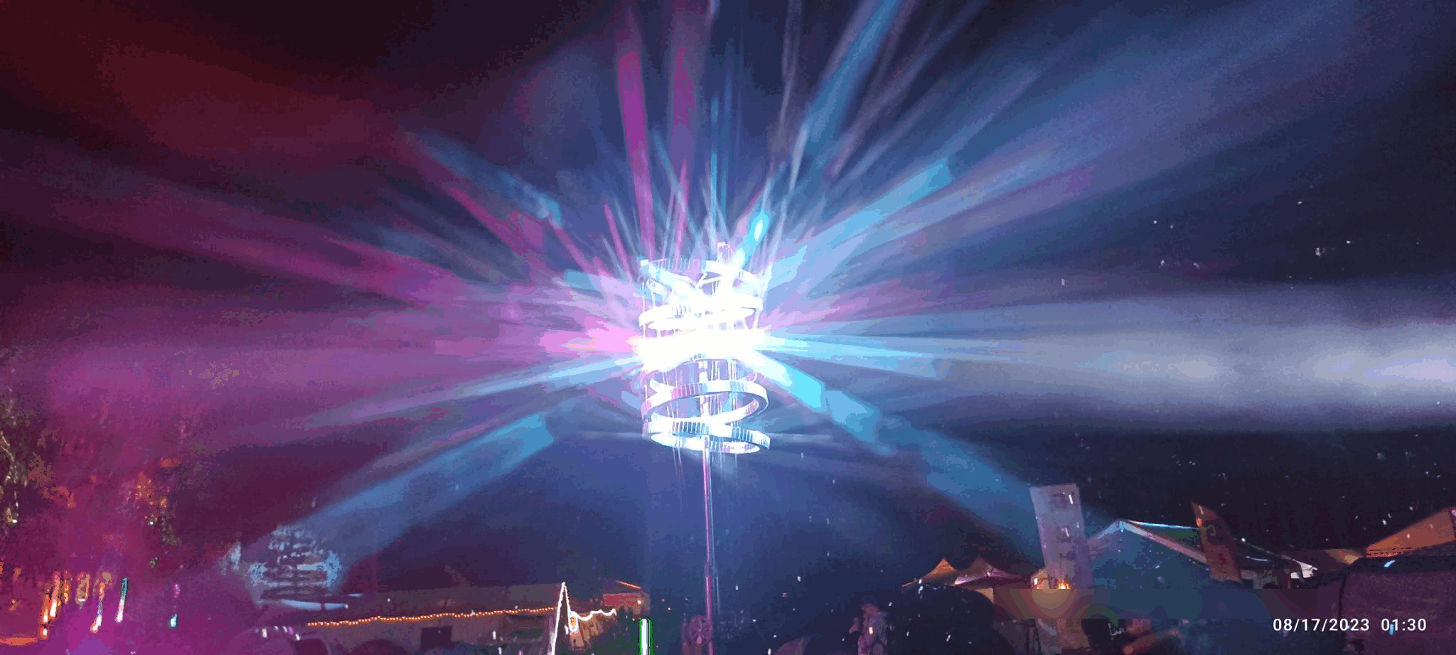 A tower of mirrors being hit by purple/blue and pink light beams, reflecting them all over the place